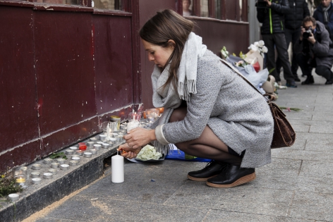  A girl lights a candle in memory of the victims outside the Carillon bar in Paris, France.